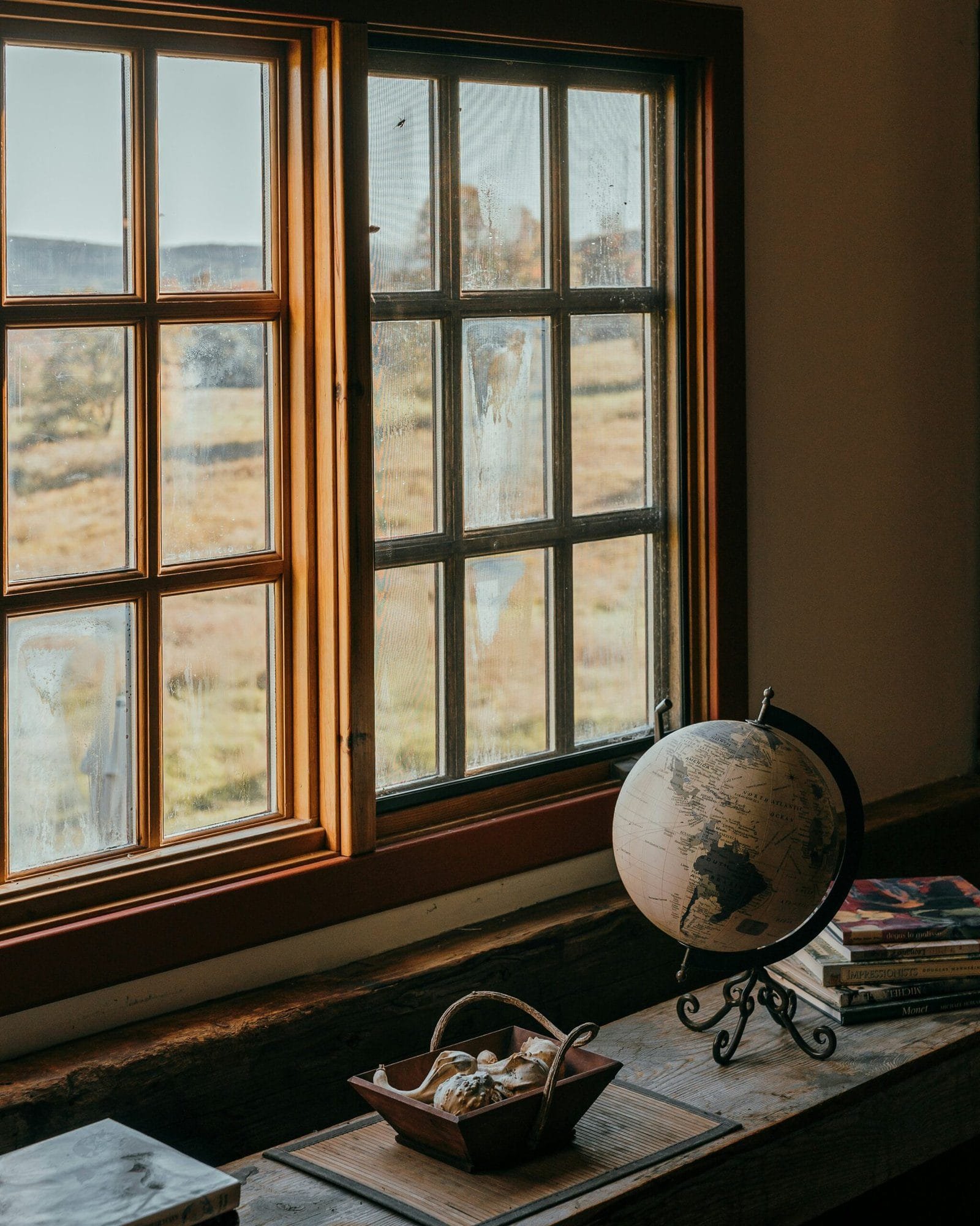 a globe sitting on top of a wooden table next to a window