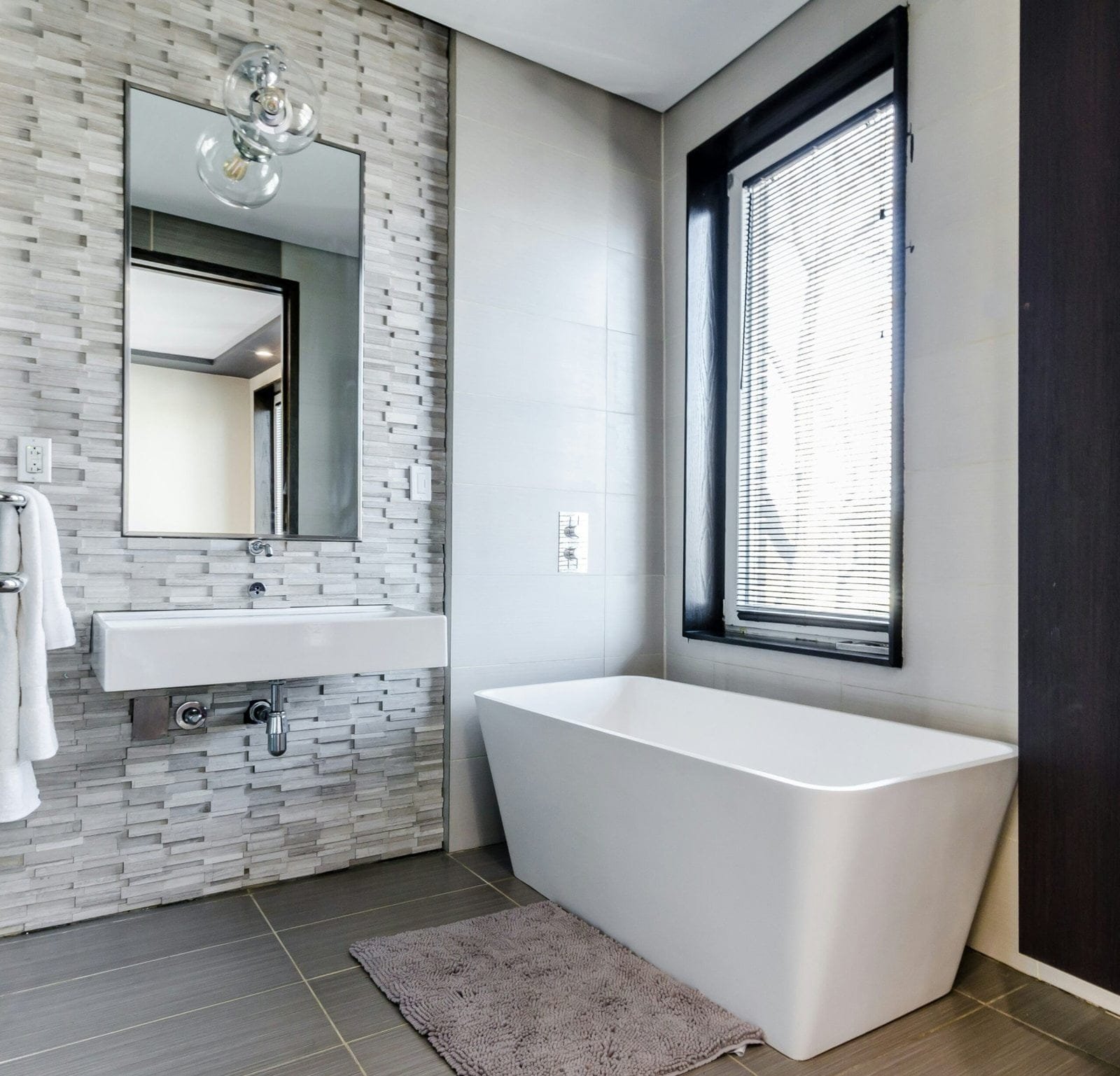 white ceramic bathtub near white framed window