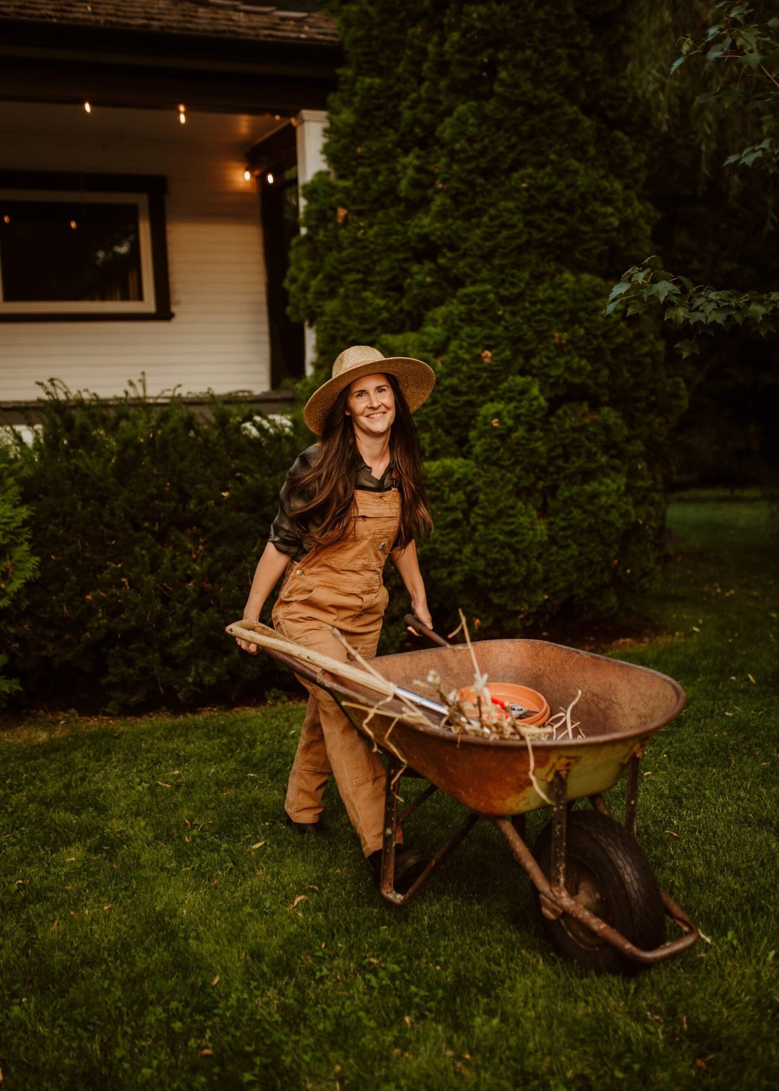 A woman in a hat holding a wheelbarrow